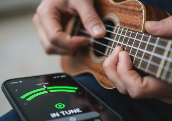 A user tunes a ukulele using an online tuner, green light