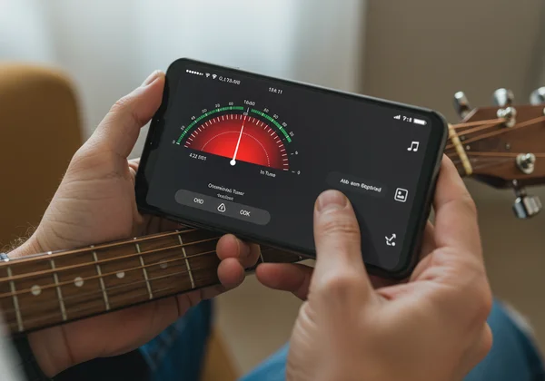 Personne utilisant un téléphone portable pour accorder une guitare