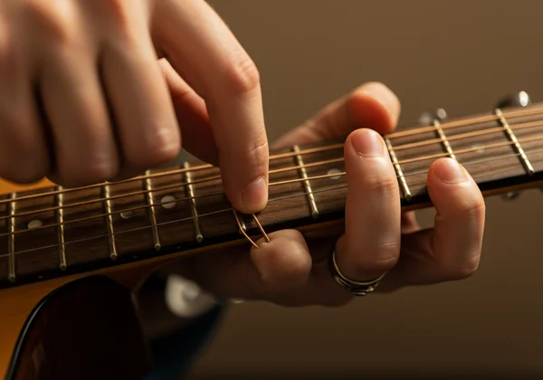 Hand gently stretching a guitar string for tuning stability